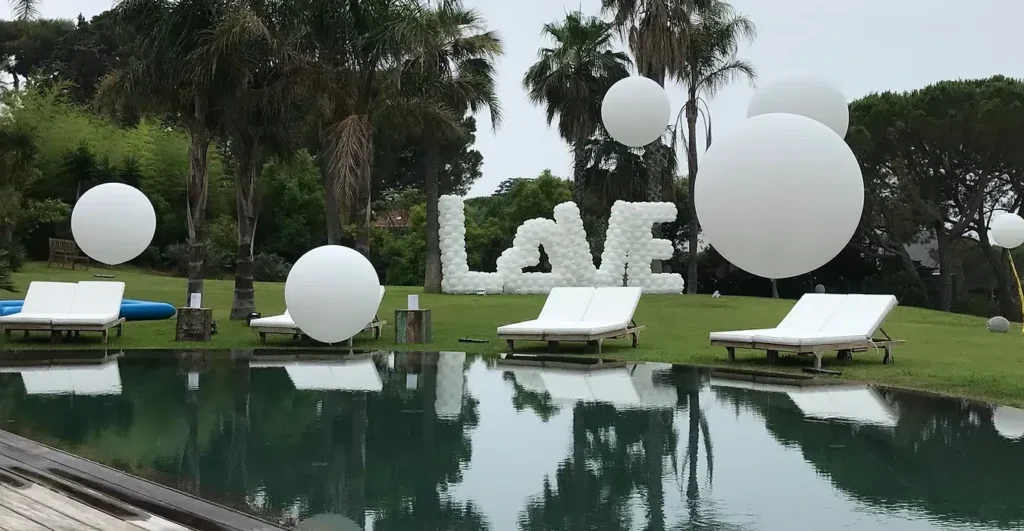Palloncini bianchi giganti e lettere LOVE accanto a una piscina in giardino