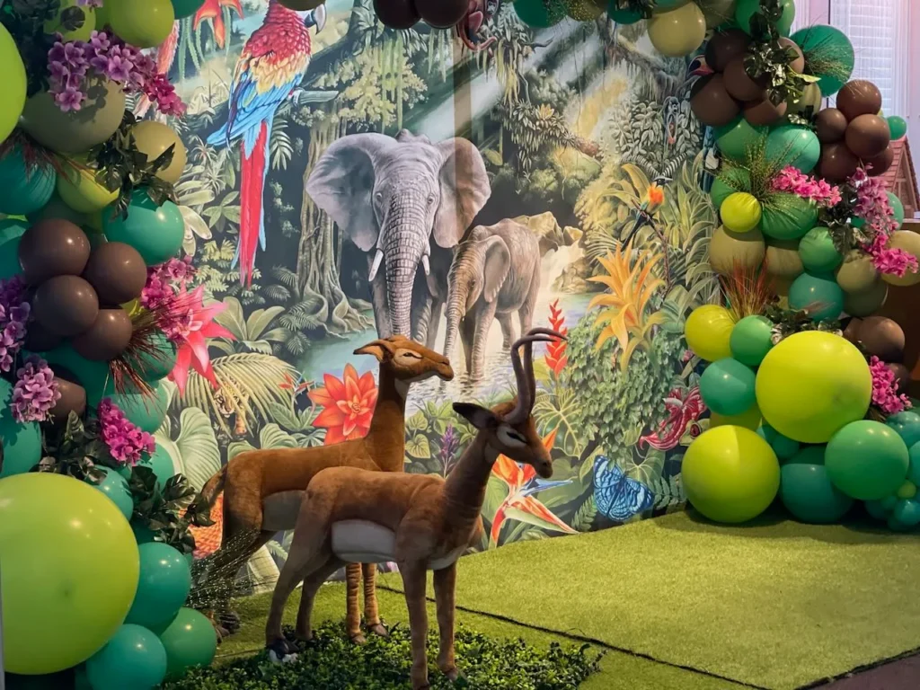 Décor sur le thème safari avec guirlandes de ballons, figurines d’antilopes et gazon artificiel