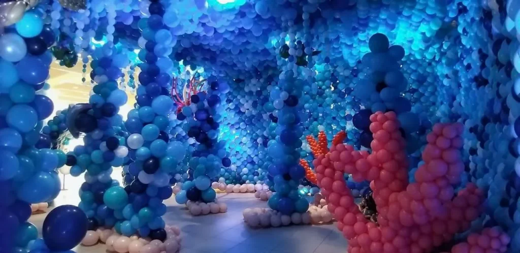Installation immersive de ballons sur le th&egrave;me des fonds marins avec un r&eacute;cif de corail rose